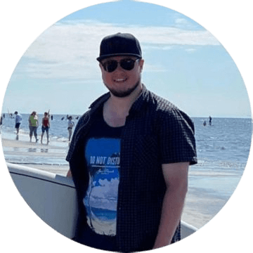 Porträt eines jungen Mannes mit Sonnenbrille und Basecap am Strand bei sonnigem Wetter