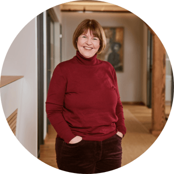 Porträt einer Frau mit kurzem, braunem Haar und rotem Rollkragenpullover in einem modernen Büro