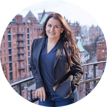 Frau mit dunklem Haar auf Balkon mit Blick auf die Speicherstadt in Hamburg