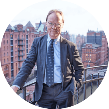 Mann mit Brille im Anzug auf Balkon mit Blick auf die Hamburger Speicherstadt