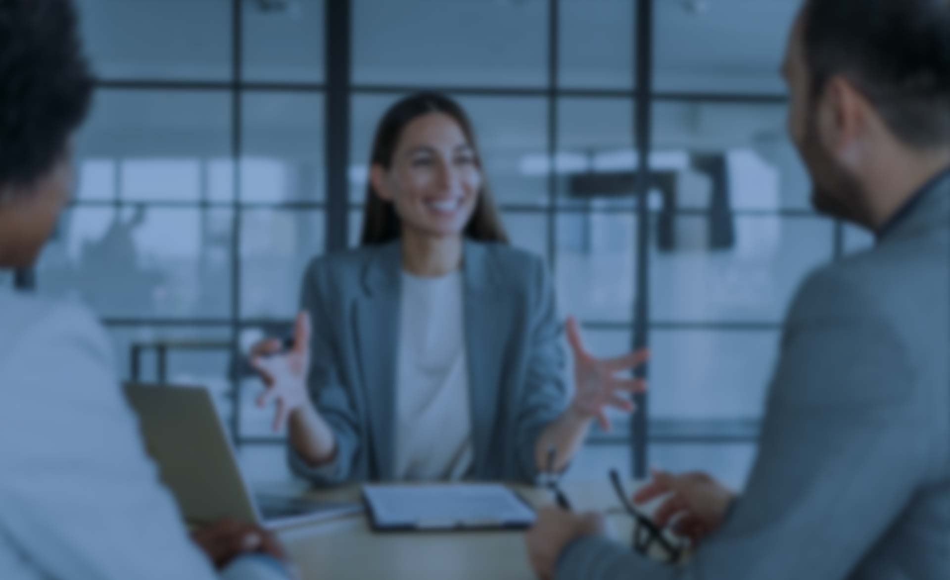 Verschwommenes Bild von drei Personen in Businesskleidung in einem Gespräch am Konferenztisch